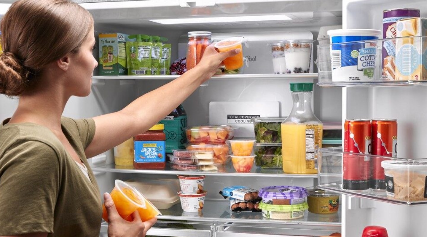 Woman taking food out of a refrigerator Woman taking food out of a refrigerator